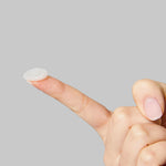 A finger with an Avarelle Multi-Dart Patch resting on the tip against a gray background.