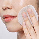Woman applying Avarelle's Total Calming Toner Pads on her cheek.